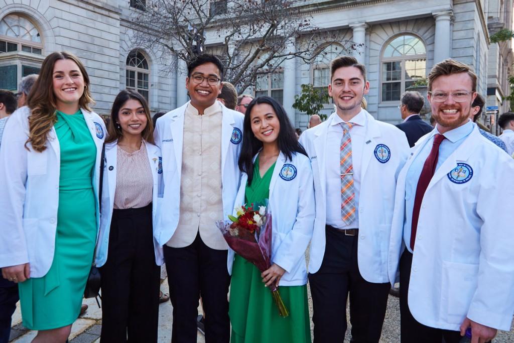 A group of C O M students in their white coats
